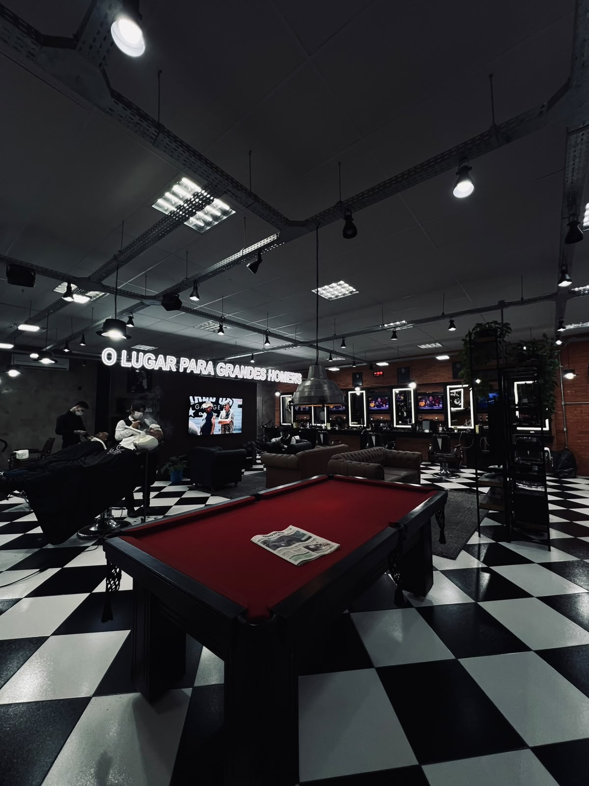 Interior escuro da La Mafia Barbearia Petrópolis, Porto Alegre com navalha em primeiro plano