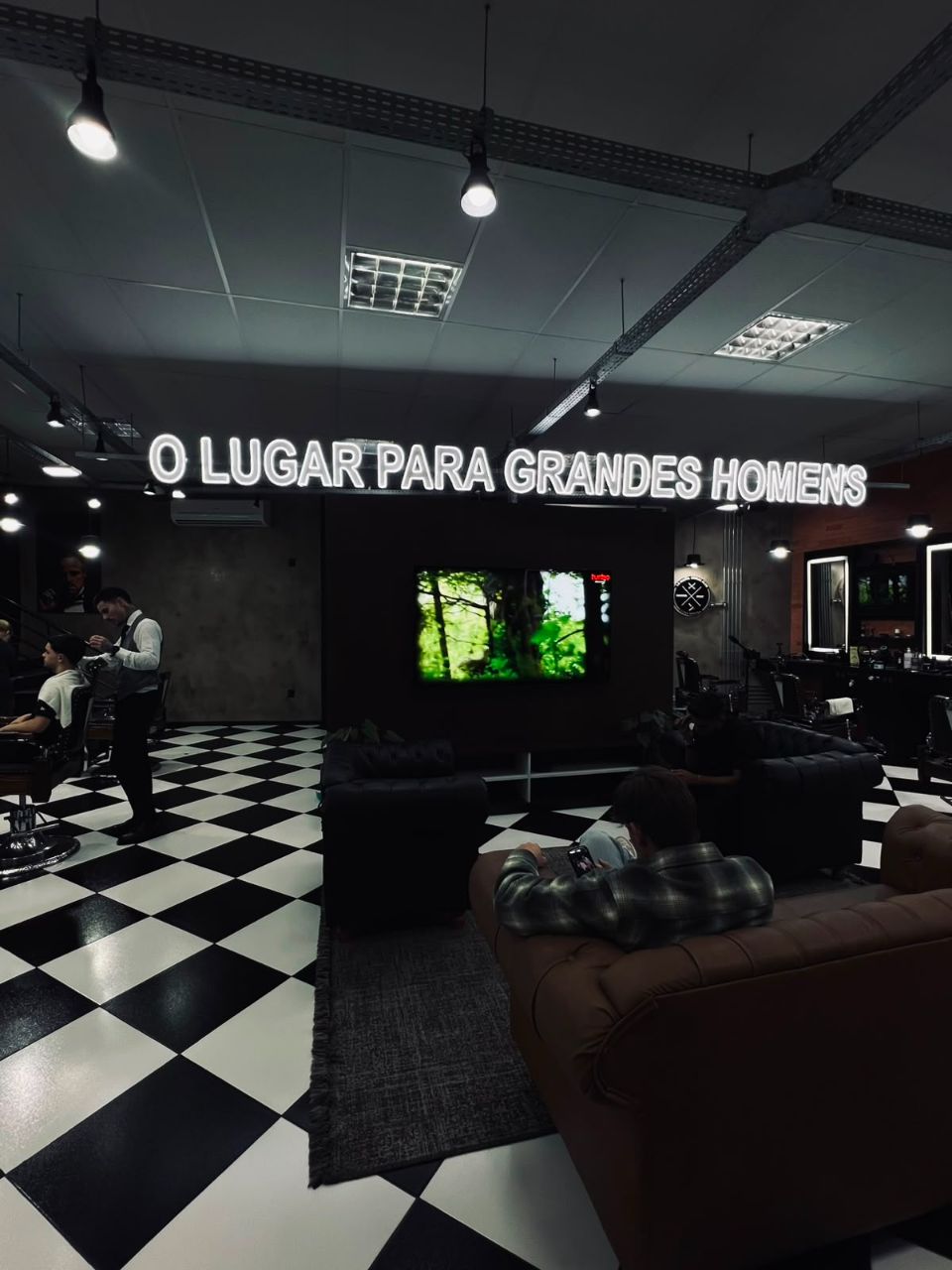 Neon 'O lugar para grandes homens' sobre o lounge com telão