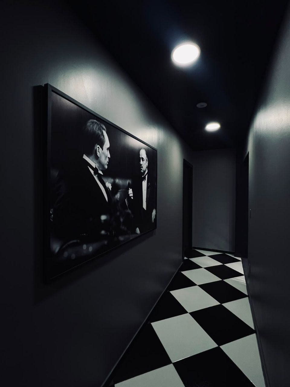 Corredor com quadro do Poderoso Chefão e piso xadrez