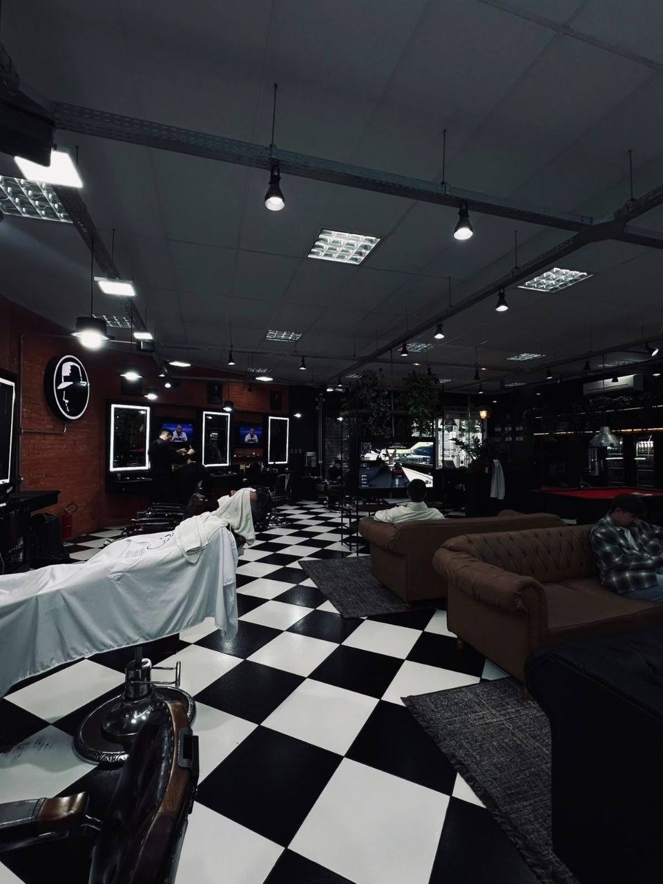 Salão cheio da La Mafia Petrópolis com lounge de sofás e piso xadrez